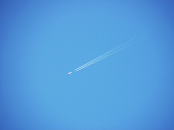 空を飛ぶ飛行機と、縦に二つ伸びる飛行機雲
