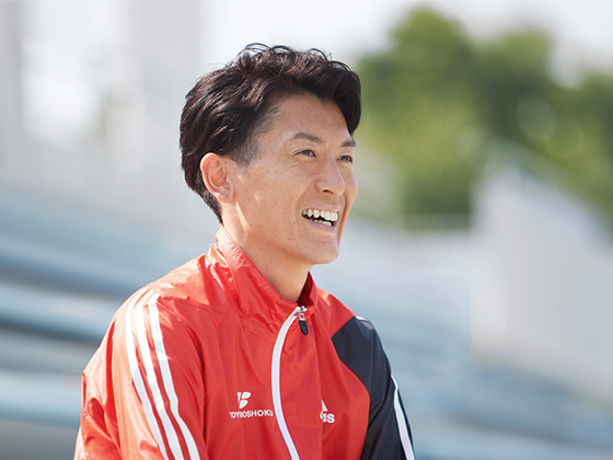 陸上競技場の観戦場所で笑顔で語る糟谷悟さん