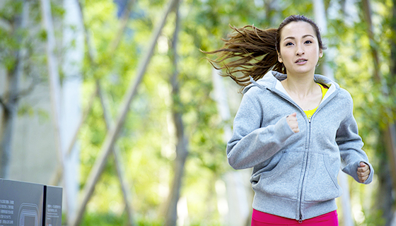 ポニーテールでグレーのパーカーを着てジョギングをする女性の写真